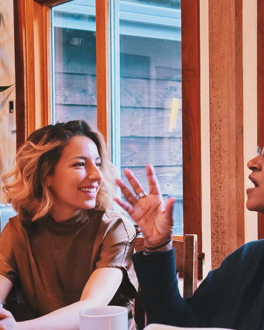 Two women talking over coffee by the window