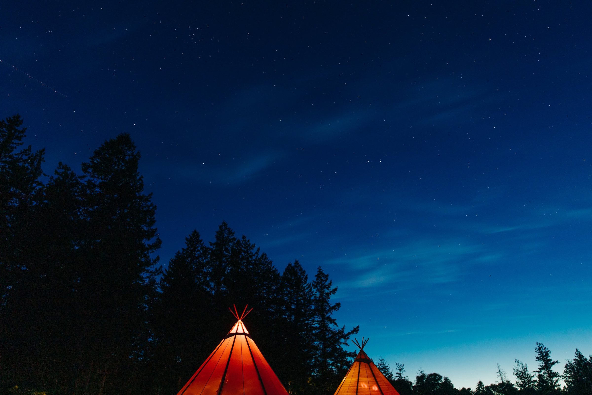 Interior of glamping tent with queen bed, decorative rug, and lanterns